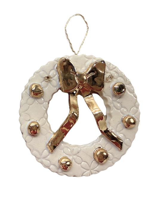 Decorative white wreath ornament with gold bow and accents on a white background